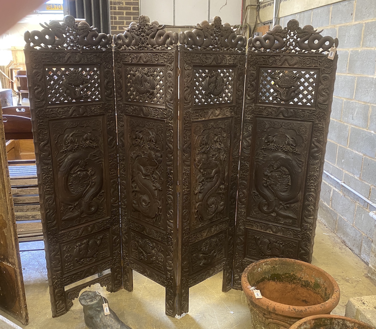 A Chinese carved hardwood four fold dressing screen, each panel width 56cm, height 199cm